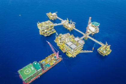 Vista aérea de uma plataforma offshore em alto-mar, com estruturas industriais e equipamentos de produção.