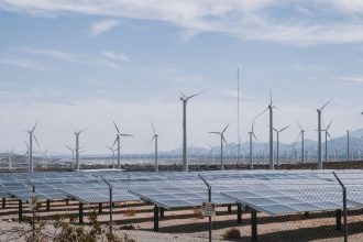 Parque de energia renovável com turbinas eólicas e painéis solares sob céu aberto.