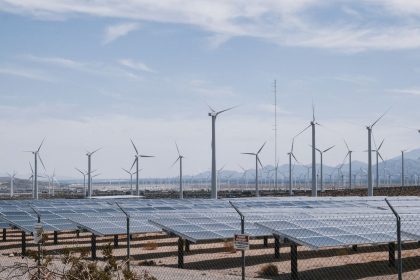 Parque de energia renovável com turbinas eólicas e painéis solares sob céu aberto.
