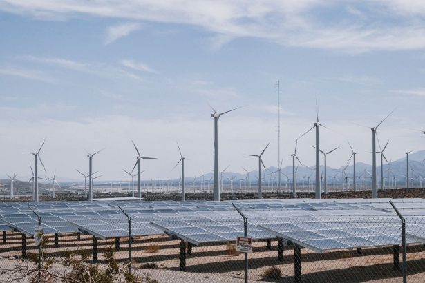 Parque de energia renovável com turbinas eólicas e painéis solares sob céu aberto.