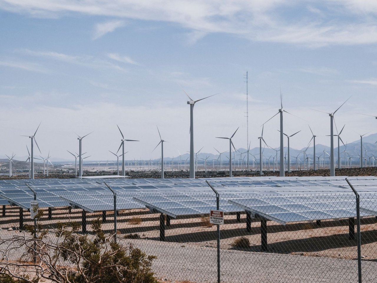 Parque de energia renovável com turbinas eólicas e painéis solares sob céu aberto.