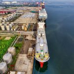 Vista aérea de petroleiros junto a instalações industriais de armazenamento de petróleo em um porto.