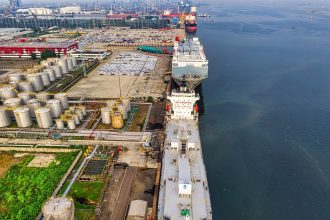 Vista aérea de petroleiros junto a instalações industriais de armazenamento de petróleo em um porto.