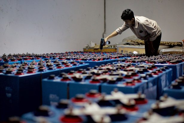 Trabalhador verifica um conjunto de baterias industriais dentro de uma instalação de armazenamento de energia.