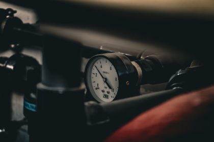 Close de um manômetro instalado em um sistema de tubulações industriais, indicando a pressão em bar.